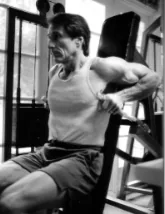 Frank Zane performing a seated cable triceps exercise.