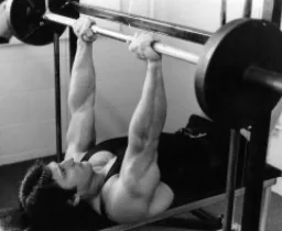 Frank Zane locking out a barbell bench press.