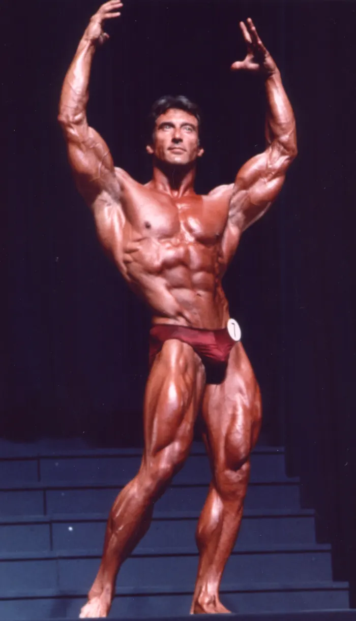 A dramatic full-color victory pose on the winner's steps, arms raised, contestant number 7.