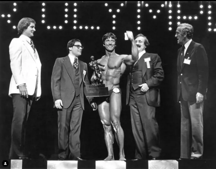 A genuine on-stage award-ceremony photo of Zane accepting the Mr. Olympia trophy.