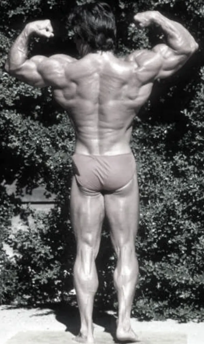 The iconic black-and-white studio treatment of the classic back double-biceps pose.