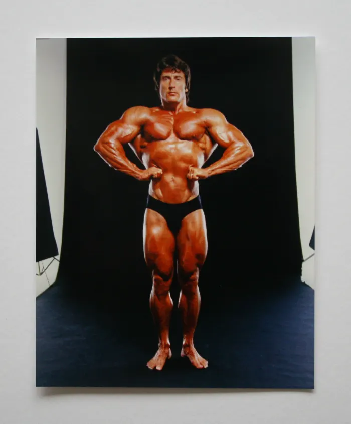 A sharp studio front most-muscular pose with an intense direct stare against black.